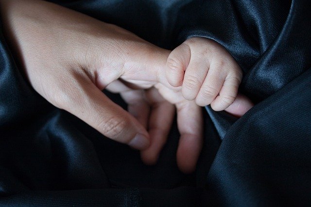 A baby holdin hand of her father